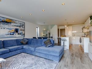 a living room with a blue couch and a kitchen at Nursery Mews in Whitstable