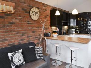 a living room with a brick wall with a clock at Oswald Lodge in Llanon