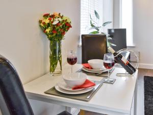 a table with two glasses of wine and a vase of flowers at Oswald Lodge in Llanon