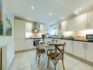 a kitchen with white cabinets and a table and chairs at Fox Cover - Uk49892 in Preston +20 photos