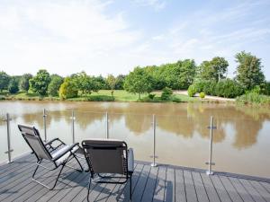 two chairs sitting on a dock next to a lake at Kingfisher Lodge - Uk33889 in Cullompton