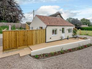 a small white house with a wooden fence at Wits End Cottage in Martin