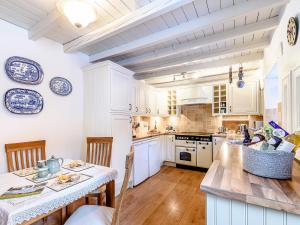 a kitchen with white cabinets and a table with chairs at Ghyll View in Gunnerside