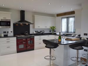 a kitchen with white cabinets and a counter with bar stools at Henry-Oscar House in Winchelsea