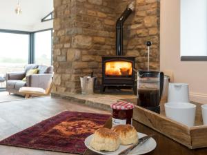 a table with a plate of food and a fireplace at Moorgate Cottage - Ukc3380 in Kelbrook