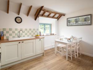 a kitchen with white cabinets and a table and a clock at Fort View - Uk32692 in Horton