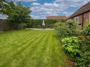 a lawn with an umbrella in a yard at Lilium Cottage in North Somercotes