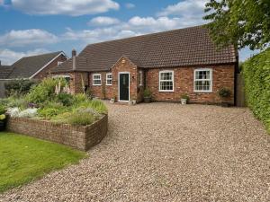 a brick house with a gravel driveway at Lilium Cottage in North Somercotes