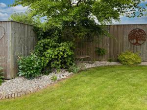 a wooden fence with a bench in a yard at Lilium Cottage in North Somercotes