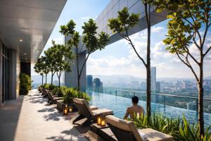 a man sitting on the infinity edge of a building overlooking a city at Royce Residence KLCC by Dormeo Destinations in Kuala Lumpur