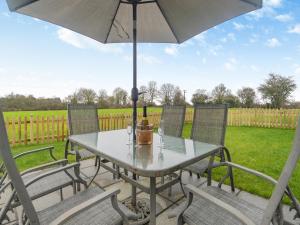 a table and chairs with an umbrella on a patio at Walcot House Stables in Diss
