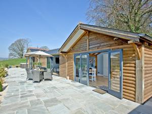 a wooden cabin with a patio and a table and chairs at Woodland View Lodge in Axminster