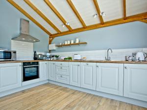 a kitchen with white cabinets and a wooden floor at Woodland View Lodge in Axminster