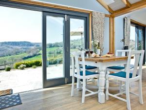 a dining room with a table and chairs and sliding glass doors at Woodland View Lodge in Axminster