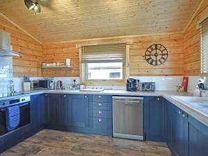 a kitchen with blue cabinets and a wooden ceiling at Stag Lodge - Uk46921 in Falkirk