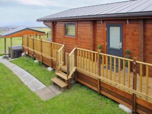 a wooden cabin with a deck and a door at Stag Lodge - Uk46921 in Falkirk