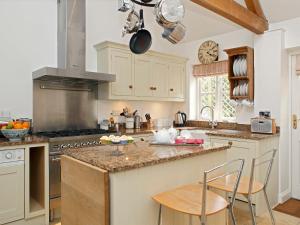 a kitchen with white cabinets and a counter with chairs at Cope - Ukc1145 in Bruern