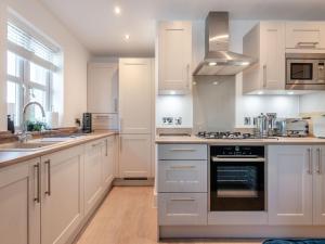 a kitchen with white cabinets and a stove top oven at Forest Acorn in Brockenhurst