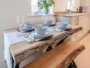 a kitchen with a wooden table with plates and wine glasses at Forest Acorn in Brockenhurst