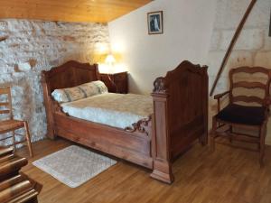 a bedroom with a wooden bed and a chair at Le Logis de bouillé in Bouillé-Courdault