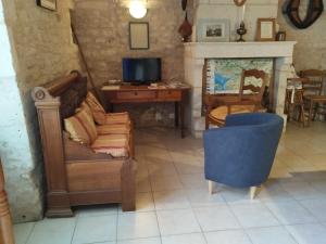 a living room with a couch and a desk and a television at Le Logis de bouillé in Bouillé-Courdault