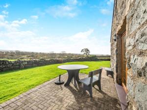 a patio with a table and two chairs and a field at Daflod - Uk48256 in Chwilog