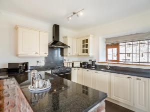 a kitchen with white cabinets and black counter tops at Daflod - Uk48256 in Chwilog