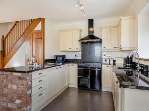 a kitchen with white cabinets and black appliances at Daflod - Uk48256 in Chwilog +7 photos