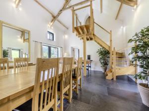 a dining room with a wooden table and a spiral staircase at Y Stabl in Llangadog
