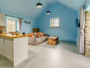 a kitchen and living room with blue walls and a couch at The Cowshed - Uk32570 in Marloes