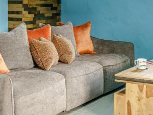 a gray couch with orange pillows on it at The Cowshed - Uk32570 in Marloes