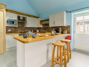 a kitchen with white cabinets and a counter with stools at The Cowshed - Uk32570 in Marloes