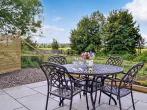 a patio table with four chairs and flowers on it at Kingfisher Cottage in Kirkton of Airlie