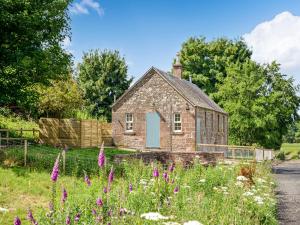an old stone house in a field with flowers at Kingfisher Cottage in Kirkton of Airlie