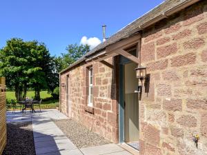 a brick building with a door and a patio at Kingfisher Cottage in Kirkton of Airlie +21 photos