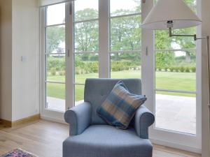 a blue chair with a pillow in a room with windows at The Stables - Uk11108 in Montrose