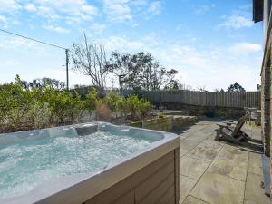 a jacuzzi bathtub in a backyard with a fence at Gwithian House in Port Isaac