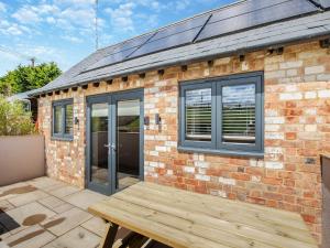 a brick house with a wooden deck in front of it at The Old Stables 2 - Uk46683 in Shipton under Wychwood