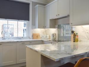 a kitchen with white cabinets and a marble counter top at The House At One Warwick Park in Royal Tunbridge Wells +10 photos