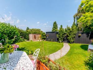a garden with a table and chairs and a lawn at Poppy's Cottage in Faversham
