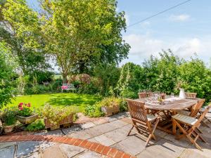 a patio with a table and chairs in a garden at Poppy's Cottage in Faversham