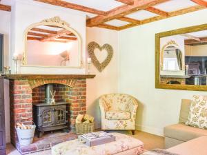 a living room with a fireplace and a mirror at Greenbank Cottage in Burley