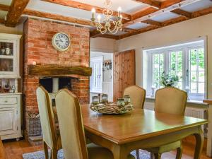 a dining room with a wooden table and a fireplace at Greenbank Cottage in Burley