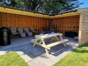 a picnic table on a patio with chairs at Dronefield Lodge in Pitney