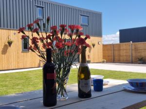 two bottles of wine and a vase of flowers on a table at Dronefield Lodge in Pitney