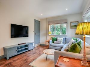 a living room with a couch and a tv at Keeds Cottage in Pulborough