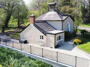 a small white house behind a fence at The Lodge in Wonastow