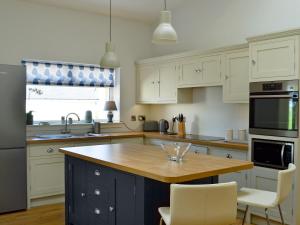 a kitchen with white cabinets and a wooden counter top at Yonderton Mcgill Cottage - Uk11182 in Hollybush