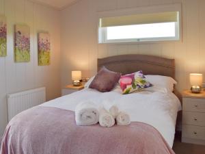 a bedroom with a bed with two towels on it at Willow Lodge - Uk13637 in Creetown