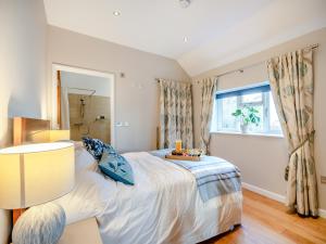a bedroom with a bed with a lamp and a window at Larks Nest in Wortham +13 photos
